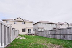 Rear exterior featuring light-toned siding, a rear wood deck, and a grass lawn - 