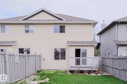 Rear exterior featuring beige horizontal siding, white-framed windows, and a multi-level roofline - 