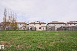Expansive green space with distant residential properties featuring wood fencing - 