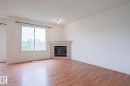 Bright interior space featuring wood-finish flooring and white walls - 1627 Melrose Place Sw, Edmonton, AB  - Indoor Photo Showing Living Room With Fireplace 