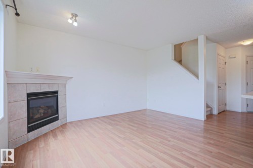 Light wood-finish flooring throughout the room - 1627 Melrose Place Sw, Edmonton, AB - Indoor With Fireplace