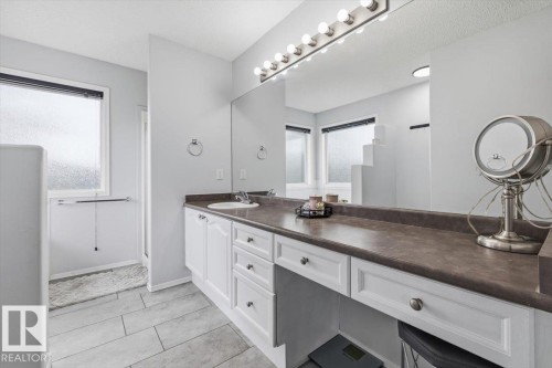 Bathroom featuring a white vanity with multiple storage drawers, a single basin sink, and a dark countertop - 3570 Mclean Crescent, Edmonton, AB - Indoor