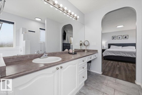 White vanity with ample counter space and an integrated sink, featuring a large mirror with strip lighting - 3570 Mclean Crescent, Edmonton, AB - Indoor Photo Showing Bathroom