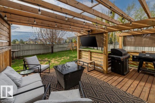 Expansive wood deck with a slatted pergola overhead, string lighting, and a mounted outdoor television - 3570 Mclean Crescent, Edmonton, AB - Outdoor With Deck Patio Veranda With Exterior