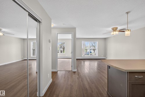 Open-concept living space featuring wood-finish flooring, light gray walls, and multiple ceiling fans - 215 6084 Stanton Drive, Edmonton, AB - Indoor Photo Showing Other Room