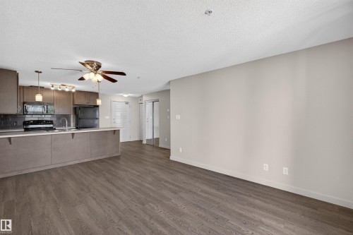 Open-concept living area with wood-finish flooring extending into the kitchen - 215 6084 Stanton Drive, Edmonton, AB - Indoor Photo Showing Kitchen
