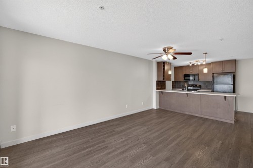 Open-concept living area featuring wood-finish flooring, a contemporary ceiling fan, and recessed lighting - 215 6084 Stanton Drive, Edmonton, AB - Indoor Photo Showing Kitchen