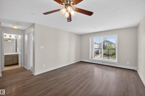 Spacious room featuring wood-finish flooring, a ceiling fan with integrated lighting, and neutral wall tones - 215 6084 Stanton Drive, Edmonton, AB - Indoor