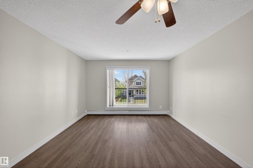 Spacious room featuring wood-finish flooring, light neutral wall tones, and a ceiling fan with integrated lighting - 215 6084 Stanton Drive, Edmonton, AB - Indoor Photo Showing Other Room