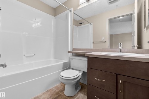 Bathroom featuring a white bathtub and shower surround, a toilet, and a vanity with a recessed sink - 215 6084 Stanton Drive, Edmonton, AB - Indoor Photo Showing Bathroom