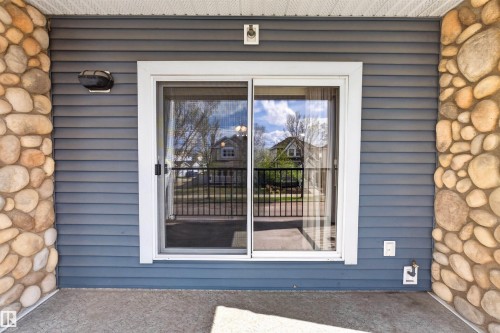 Sliding glass door with white frame, set within blue horizontal siding - 215 6084 Stanton Drive, Edmonton, AB - Outdoor With Exterior