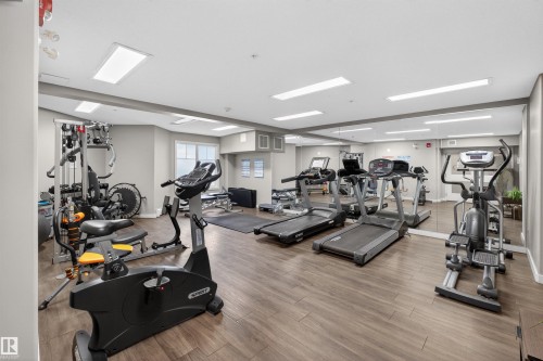 Fitness center with recessed lighting, full-wall mirror, wood-finish flooring, and light gray walls - 215 6084 Stanton Drive, Edmonton, AB - Indoor Photo Showing Gym Room