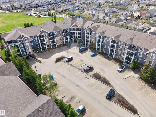 Multi-story residential complex featuring multiple exterior finishes, individual balconies, and a central courtyard with extensive parking - 215 6084 Stanton Drive, Edmonton, AB - Outdoor
