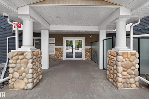 Covered entryway featuring large stone-clad columns supporting white fluted pillars - 215 6084 Stanton Drive, Edmonton, AB - 
