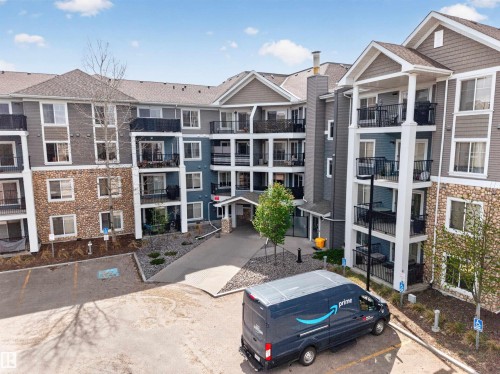 Multi-story residential building featuring stone and siding exterior, private balconies, and a paved parking area - 215 6084 Stanton Drive, Edmonton, AB - Outdoor With Facade