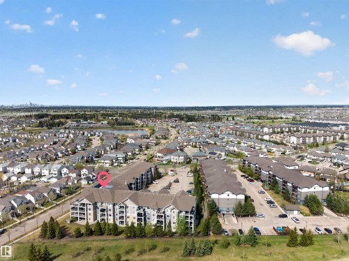 Aerial perspective showcasing a multi-story apartment building with balconies, surface parking, and surrounding residential properties - 215 6084 Stanton Drive, Edmonton, AB - Outdoor With View
