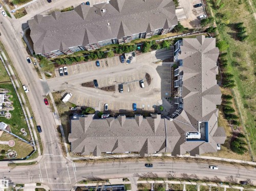 Multi-story residential complex featuring a large asphalt parking lot with marked spaces - 215 6084 Stanton Drive, Edmonton, AB -  With View