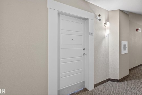 Entry door with horizontal paneling, crisp white trim, and brushed nickel hardware - 215 6084 Stanton Drive, Edmonton, AB - Indoor Photo Showing Other Room