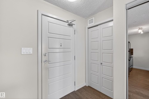 Entryway featuring a paneled door with polished chrome hardware, an overhead door closer, and light wood-finish flooring - 215 6084 Stanton Drive, Edmonton, AB - Indoor Photo Showing Other Room