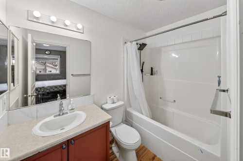 The bathroom features a vanity with a light-colored countertop and an integrated sink, a toilet, and a combination shower and bathtub - 3517 25 Street, Edmonton, AB - Indoor Photo Showing Bathroom