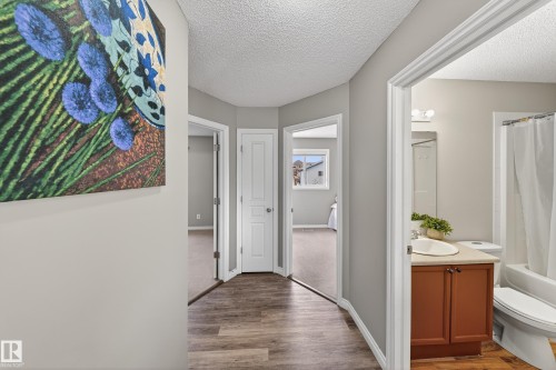 This property features wood-look flooring throughout the hallway and into the visible bathroom, which includes a white vanity with a light-colored countertop and a white toilet - 3517 25 Street, Edmonton, AB - Indoor Photo Showing Other Room