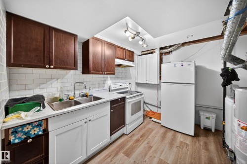 The property includes a kitchen area featuring warm wood upper cabinetry, a white subway tile backsplash, and a double basin stainless steel sink - 3517 25 Street, Edmonton, AB - Indoor Photo Showing Kitchen With Double Sink