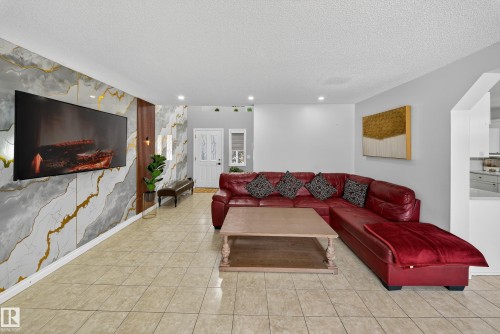 The living area features tiled flooring, recessed lighting, and a decorative wall with a mounted television - 3517 25 Street, Edmonton, AB - Indoor Photo Showing Living Room