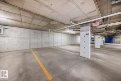Parking garage featuring concrete walls, concrete flooring with painted yellow lines, and exposed overhead piping - 