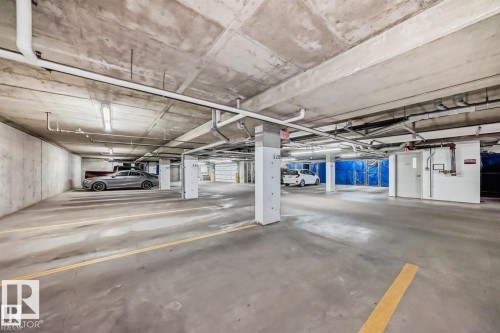 Underground parking facility featuring concrete flooring and ceiling, white support columns, and fluorescent lighting - 327 508 Griesbach Parade, Edmonton, AB - Indoor Photo Showing Garage
