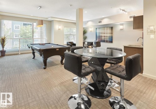 Open-concept amenity space featuring patterned carpet flooring and a generously sized window wall - 327 508 Griesbach Parade, Edmonton, AB - Indoor Photo Showing Other Room