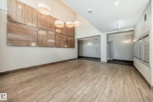 Foyer featuring wood-finish tile flooring, recessed lighting, and wall-mounted mailboxes - 327 508 Griesbach Parade, Edmonton, AB - Indoor Photo Showing Other Room