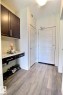 Entryway featuring wood-finish flooring, a wall-mounted dark wood-finish cabinet with a granite-look countertop, recessed lighting, and a solid entry door with a multi-paneled design - 327 508 Griesbach Parade, Edmonton, AB  - Indoor Photo Showing Other Room 