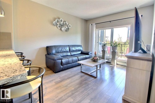 Living area with light wood-finish flooring and a sliding glass door to the exterior - 327 508 Griesbach Parade, Edmonton, AB - Indoor Photo Showing Living Room