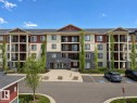 Multi-story residential building featuring a stone facade, red siding, and light-colored siding accents - 422 5816 Mullen Place, Edmonton, AB  - Outdoor With Facade 