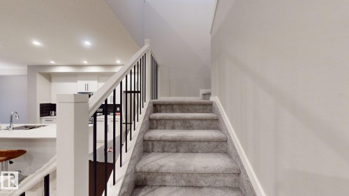 The property features a staircase with carpeted steps and a white railing with dark vertical balusters - 607 31 Avenue, Edmonton, AB - Indoor Photo Showing Other Room
