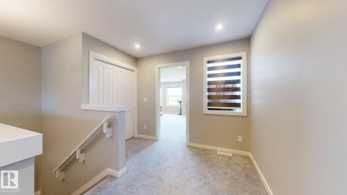 The property features a hallway with light-colored carpeting, a window with horizontal blinds, and a white closet with bi-fold doors - 607 31 Avenue, Edmonton, AB - Indoor Photo Showing Other Room