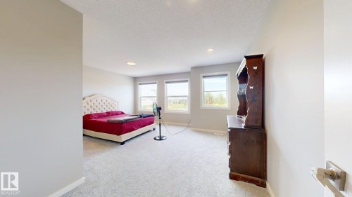 This spacious room features light-colored carpeting, three windows providing natural light, and recessed ceiling lights - 607 31 Avenue, Edmonton, AB - Indoor