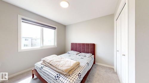 This room features light gray walls, a window with a dark roller blind, a textured bed frame, and white bi-fold closet doors - 607 31 Avenue, Edmonton, AB - Indoor Photo Showing Bedroom