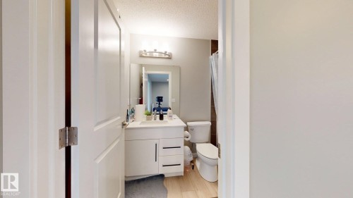 The bathroom features a vanity with a white countertop and a mirror, a toilet, and a tiled shower area with a shower curtain - 607 31 Avenue, Edmonton, AB - Indoor Photo Showing Bathroom