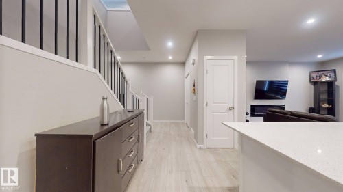 The property features light-toned flooring, a staircase with black railings, and recessed lighting throughout - 607 31 Avenue, Edmonton, AB - Indoor Photo Showing Other Room