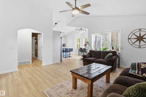 Vaulted ceiling living area featuring wood-finish flooring, a ceiling fan, and large windows - 396 Kananaskis Way, Devon, AB - Indoor Photo Showing Living Room