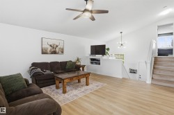Spacious living area featuring a vaulted ceiling, wood-finish flooring, and a modern ceiling fan - 