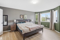 Spacious room featuring light wood-finish flooring, a contemporary ceiling light fixture, and large windows with privacy drapes - 