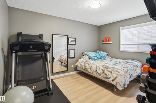 Room featuring light wood-finish flooring, a double window with blinds, and a flush-mount ceiling light - 396 Kananaskis Way, Devon, AB - Indoor Photo Showing Bedroom