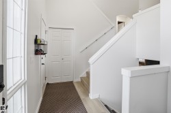 Entryway featuring a staircase with a prominent white railing, wood-finish flooring, and white bi-fold closet doors - 