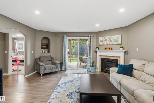 Spacious living area featuring wood-finish flooring, recessed lighting, and a fireplace with a white mantel and tile surround - 396 Kananaskis Way, Devon, AB - Indoor Photo Showing Living Room With Fireplace