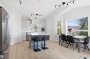 Kitchen and dining area featuring light wood-finish flooring, vaulted ceilings, track lighting, a blue island with a white countertop, and white cabinetry - 396 Kananaskis Way, Devon, AB  - Indoor 