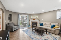 Living area featuring wood-finish flooring, a fireplace with a white mantel, recessed lighting, and a sliding glass door leading to the exterior - 