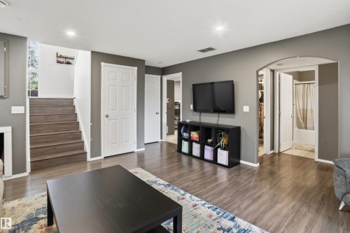 Open concept interior featuring wood-finish flooring, recessed lighting, a white six-panel door, and an arched entry - 396 Kananaskis Way, Devon, AB - Indoor Photo Showing Other Room