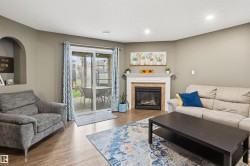 Living space featuring wood-finish flooring, a corner fireplace with a white mantel and tile surround, and a sliding glass door providing access to an outdoor patio - 